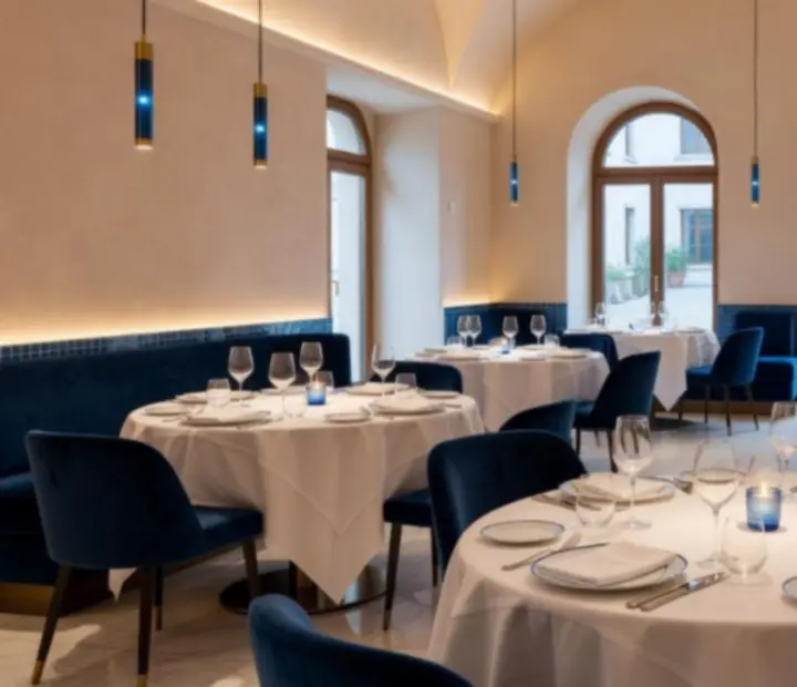 A Morq Elia világos, mediterrán hangulatú étterem belső tere porcelán-homok tónusokkal és kék részletekkel.